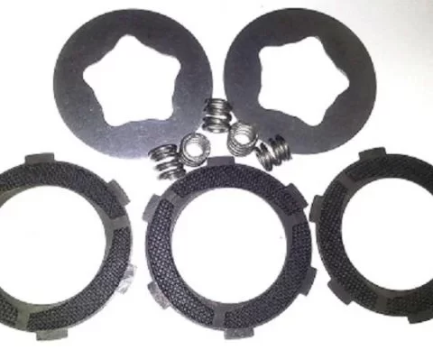 Set of motorcycle clutch plates and springs laid on a white background. Includes three friction discs and two steel plates with small springs.