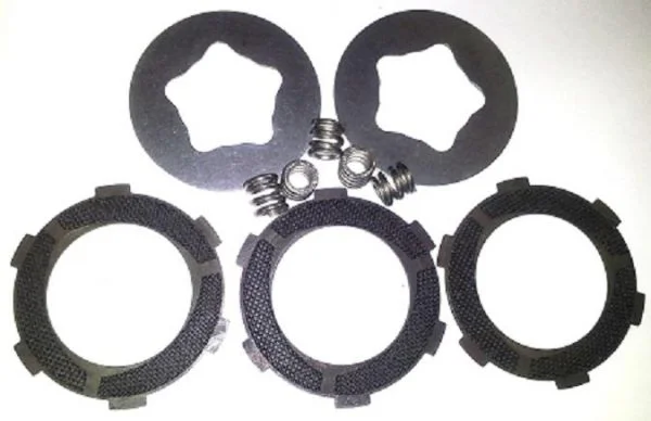 Triple-Grip-Rebuild-Kit-600x388 - Inmotion Suspension Set of motorcycle clutch plates and springs laid on a white background. Includes three friction discs and two steel plates with small springs.