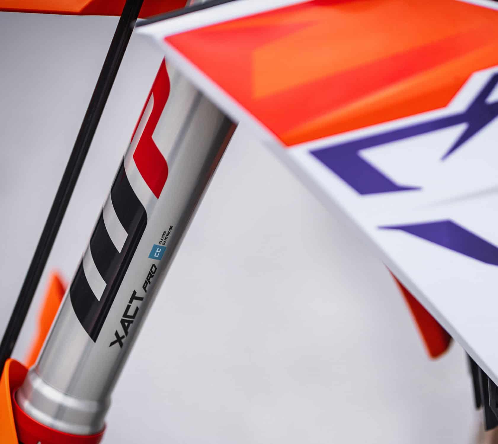 xact pro 2 - Inmotion Suspension Close-up of a mountain bike suspension fork leg with orange and white graphics.