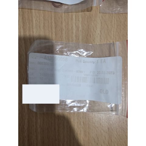 Clear resealable plastic bag on a wooden surface with a white label showing location A1306G05B and pick quantity 1 EA (barcode visible).