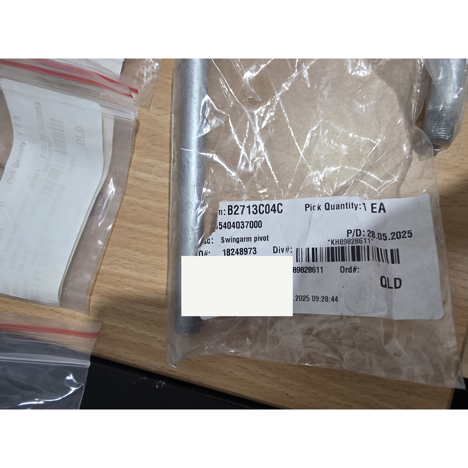 45404037000-b-cleaned - Inmotion Suspension Packaged hardware: clear plastic bag with barcode label and screw/bolt components on a wooden surface.