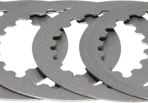 Stack of circular metal clutch plates with notched inner teeth, arranged in a overlapping fan shape.